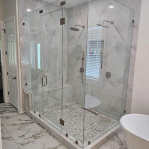 Modern bathroom with a large glass-enclosed shower, marble tile floors, and a freestanding bathtub.